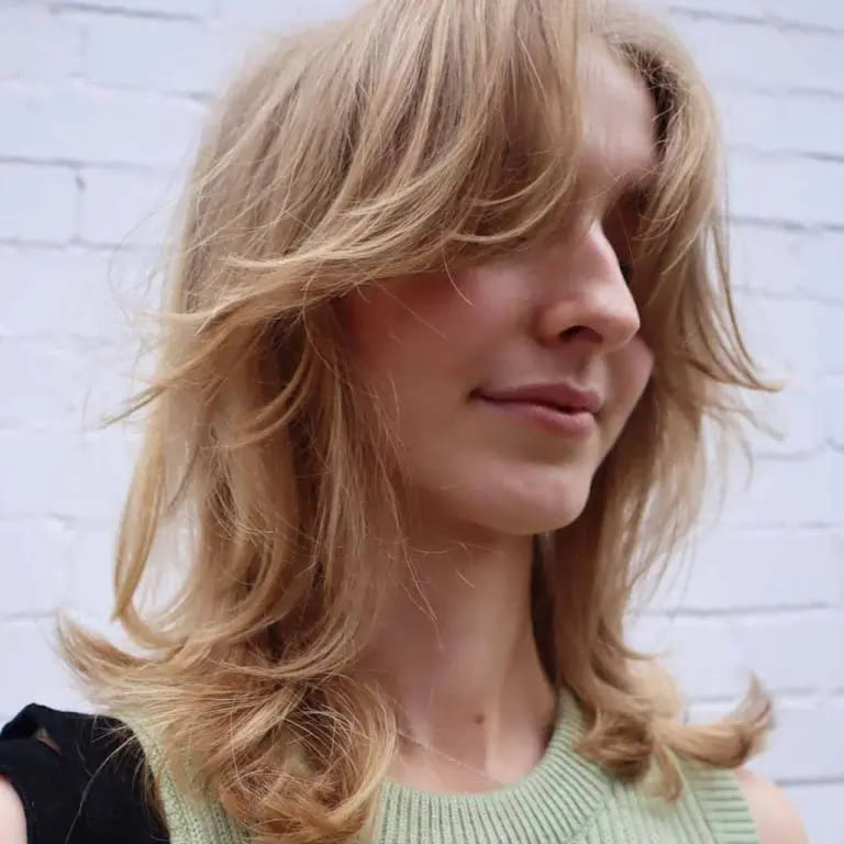 10 Best Wolf Cuts With Curtain Bangs 4 Blonde Wavy Medium Wolf Cut With Bottleneck Curtain Bangs