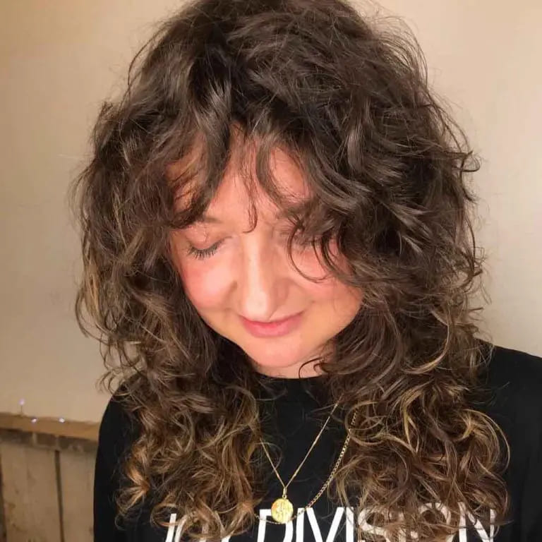10 Brown Wolf Cut Ideas for Women to Elevate Your Style! 9 Carob-Sepia Brown Mix on Curly Mullet Wolf Cut With Curly Tousled Bangs on Medium Hair