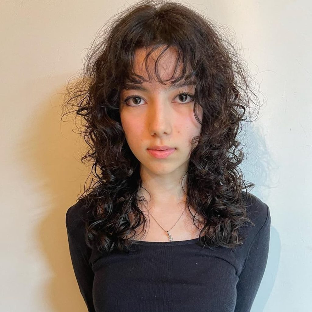 30 Best Curly Wolf Cut Ideas to Showcase Your Beautiful Curls 17 Curly Layered Wolf Cut with Wispy Bangs