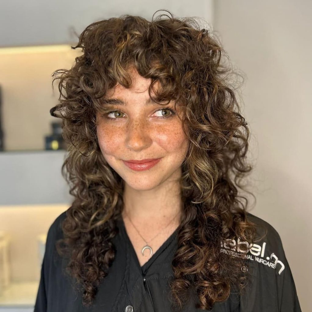 30 Best Curly Wolf Cut Ideas to Showcase Your Beautiful Curls 4 Brown Curly Haired Wolf Cut With Bangs