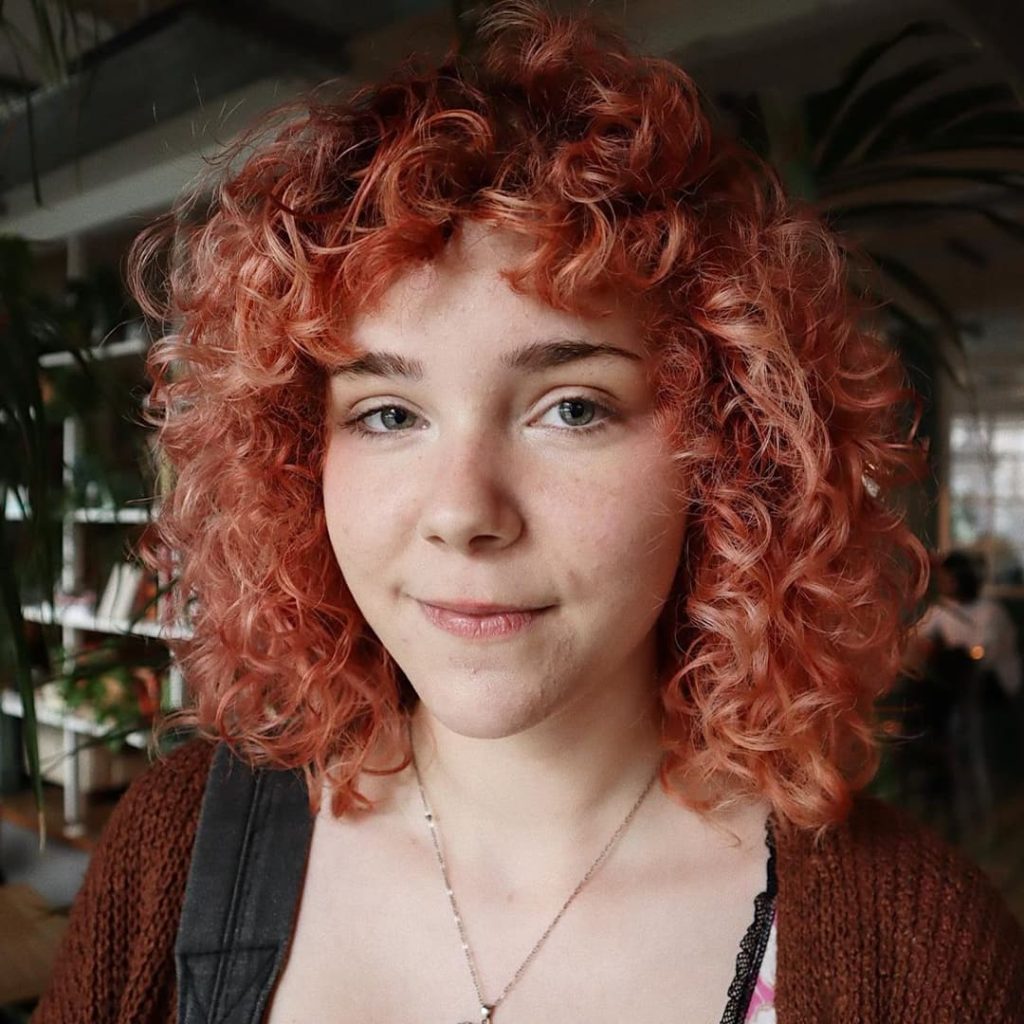 30 Best Curly Wolf Cut Ideas to Showcase Your Beautiful Curls 30 Light Pink Colored Curly Wolf Cut with Rounded Layers and Curtain Bangs