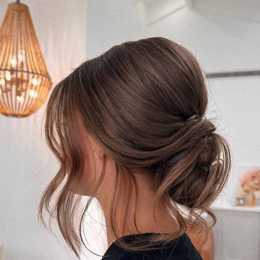 15 Stunning Bun Hairstyles for Elegance! 9 Tucked Chignon With Wavy Tendrils